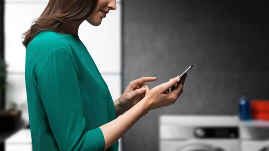 Mujer sosteniendo su teléfono usando la aplicación My AEG Care