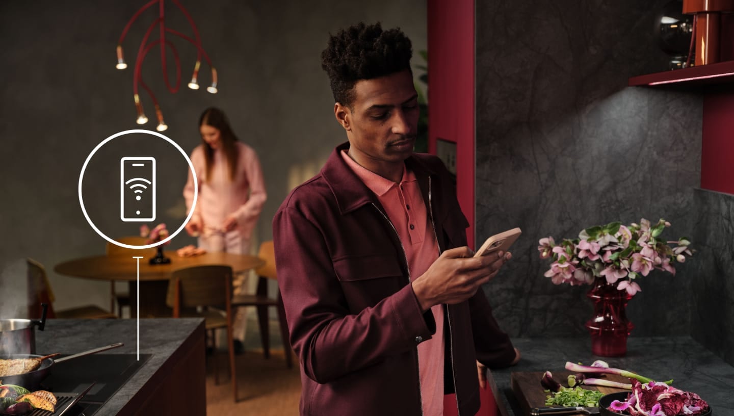 Un hombre mirando su teléfono en la cocina.