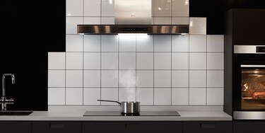 Salmón cocinándose en una placa de inducción mientras la campana de cocina extrae el vapor.