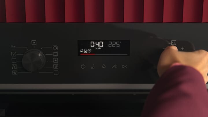 Una persona usando el panel de control de un horno.