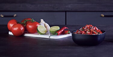 Tomates, lima, chile y ajo en una tabla de picar