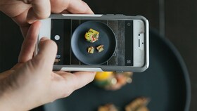 Alguien haciendo una foto de un plato de comida gourmet perfectamente presentado
