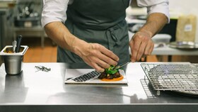 Un chef emplatando un plato de comida gourmet perfectamente presentado