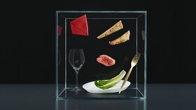 Selección de cubiertos, platos y productos en una caja de cristal que representa el fundamento de la experiencia para elevar el Sabor a Otro Nivel