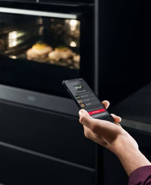 Una mano con un smartphone delante del horno