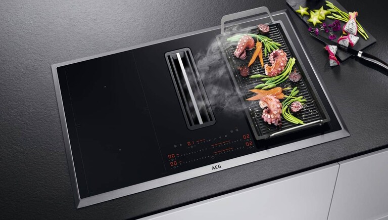 Alimentos cocinados en una plancha grill colocada sobre una placa de cocción AEG.