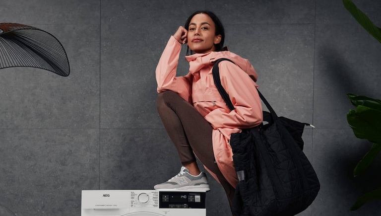 Mujer apoyada en una lavadora-secadora AEG.