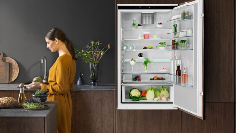 Mujer de pie en una cocina con la puerta abierta del frigorífico