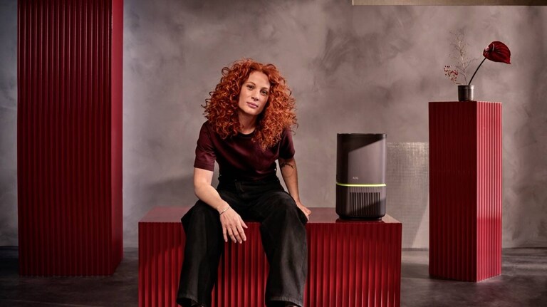 Una mujer sentada junto a un purificador de aire